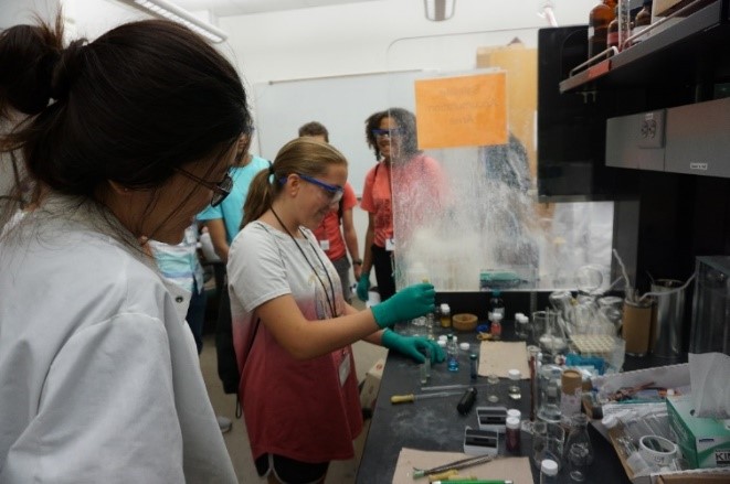 A female student doing experiment in a lab with others watching